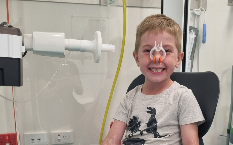 Smiling young boy sitting in lung function testing suite