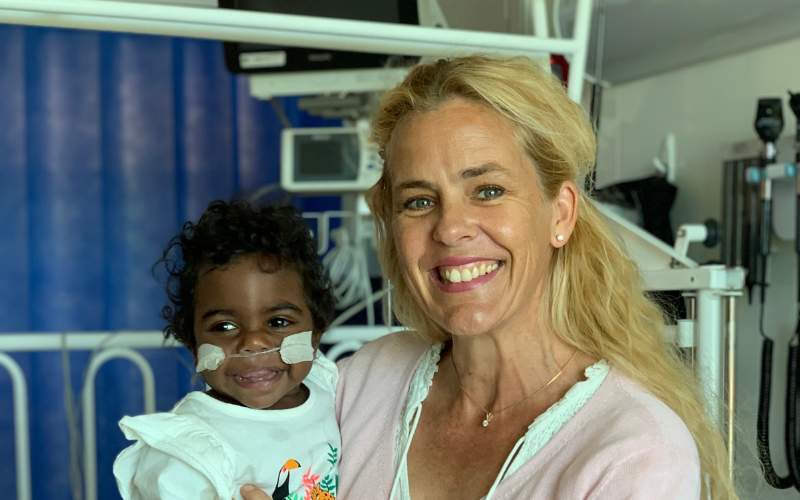 Dr Pam Laird holding a smiling Aboriginal child in a hospital setting